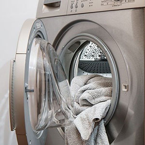 Dryer Vent Cleaning-brushed silver dryer with open door and towels inside