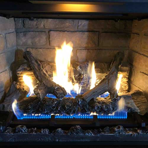 Gas logs with blue flames coming out of the pipe