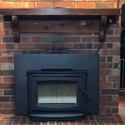 Black fireplace insert with no fire and brick surround and hearth-pretty wood mantel