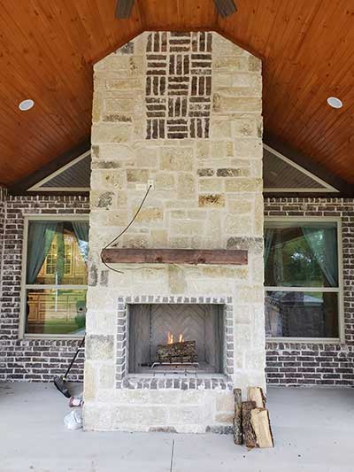 Outdoor Fireplace all the way to the chimney with design at the top on porch 