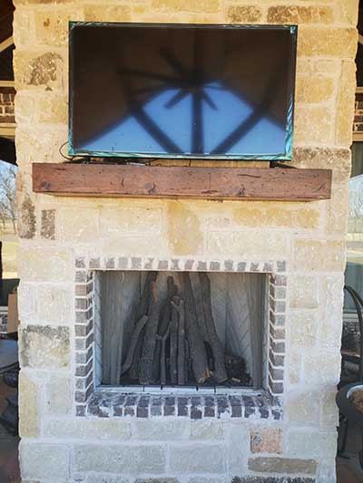 Outdoor Fireplace with mantel and tv sitting on mantel