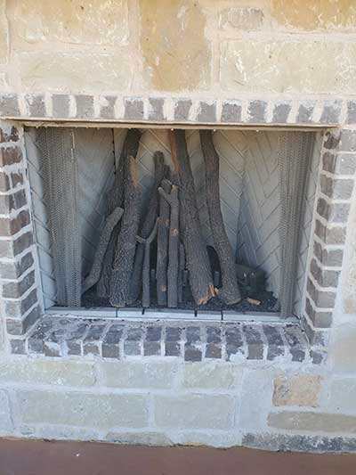 Outdoor Fireplace with brick around the firebox and stone surround with screen