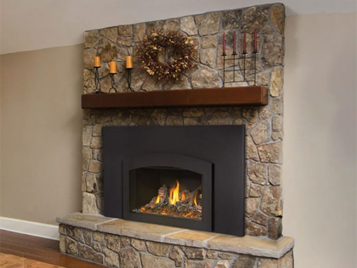 Napoleon Oakville X3 Gas Fireplace with stone surround and wooden mantel decorated with candles and wreach