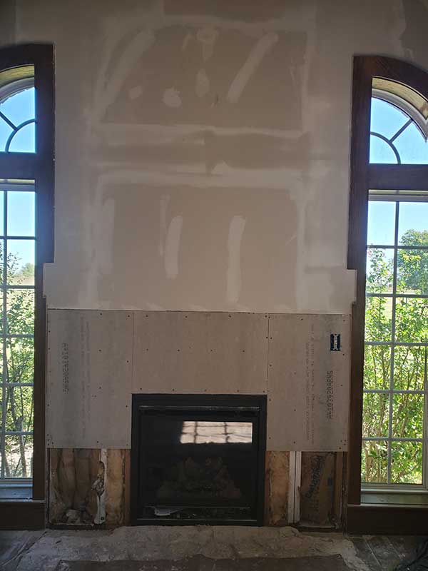 Fireplace Upgrade and Install during construction with river rock rounded hearth and arched windows on each side